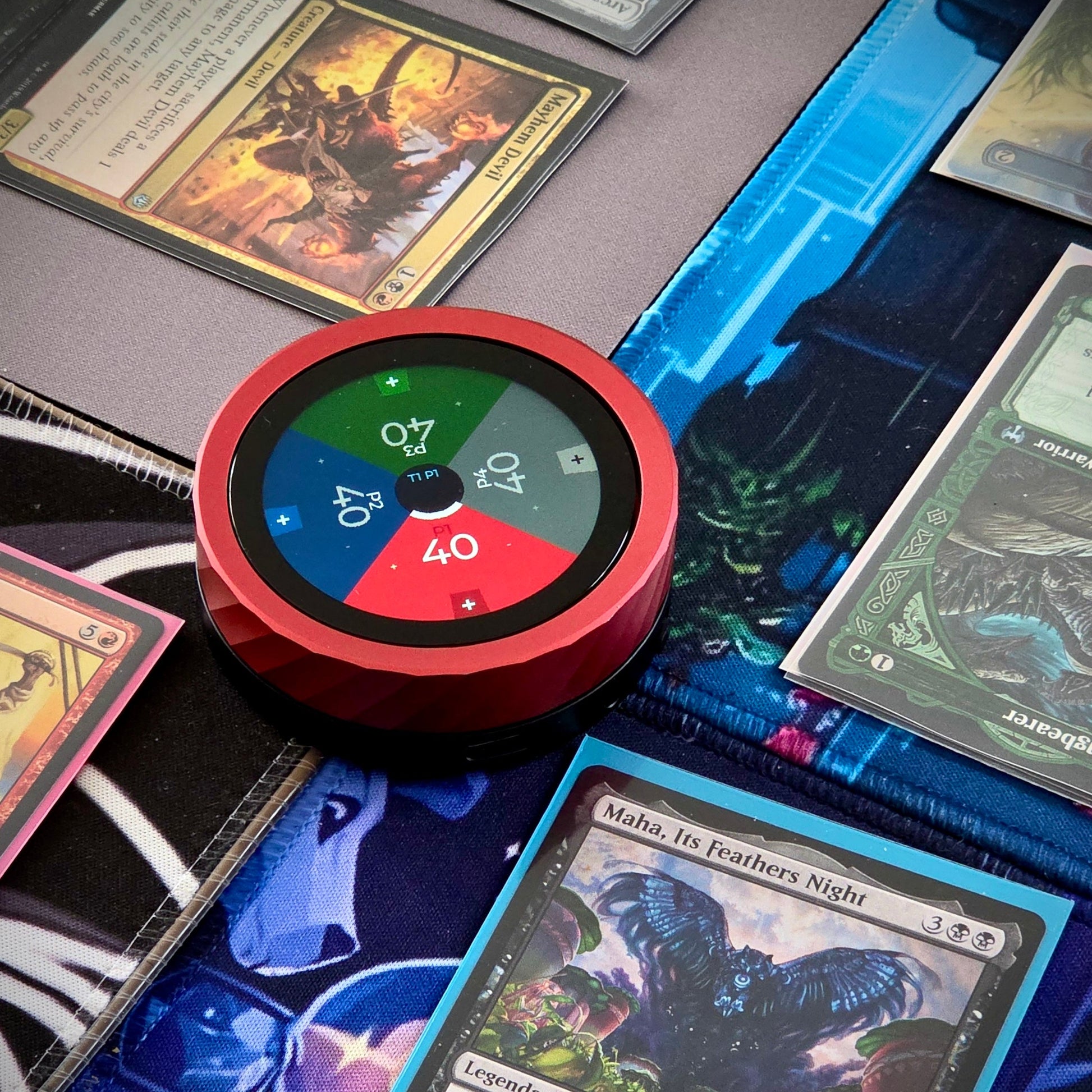 Red circular life point game device with digital display on top of trading cards